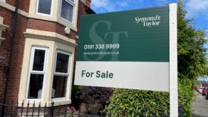 For sale sign advertising Symonds Taylor estate agents on a gosforth house